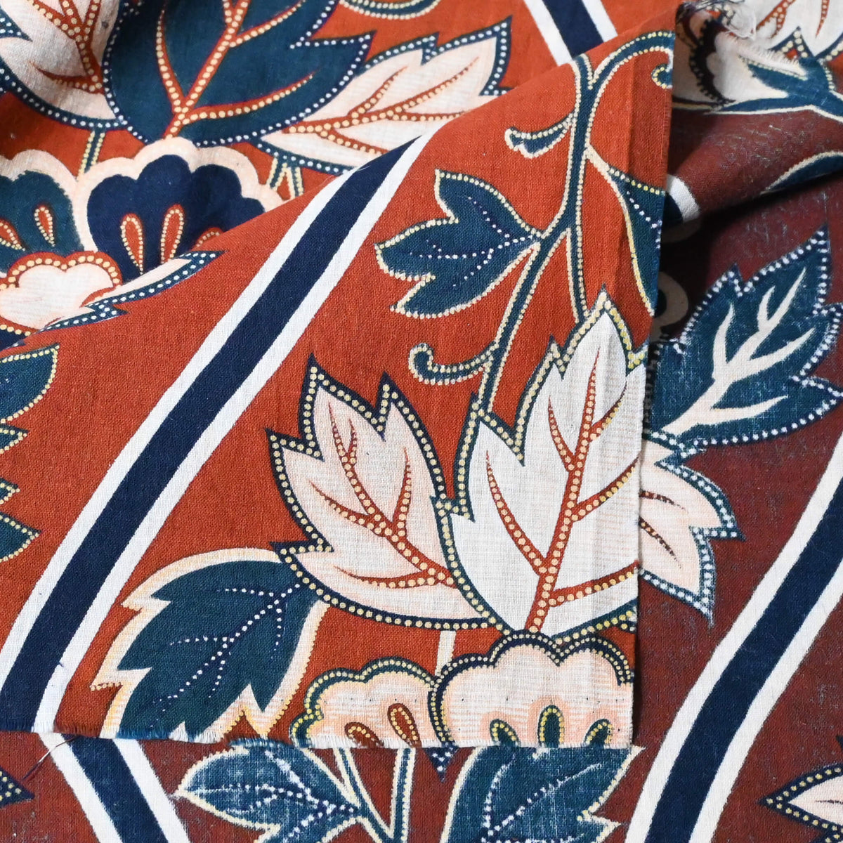 Close-up view of vintage Japanese Sarasa cotton piece with peony pattern in warm rust orange and navy, inspired by imported chintz designs.