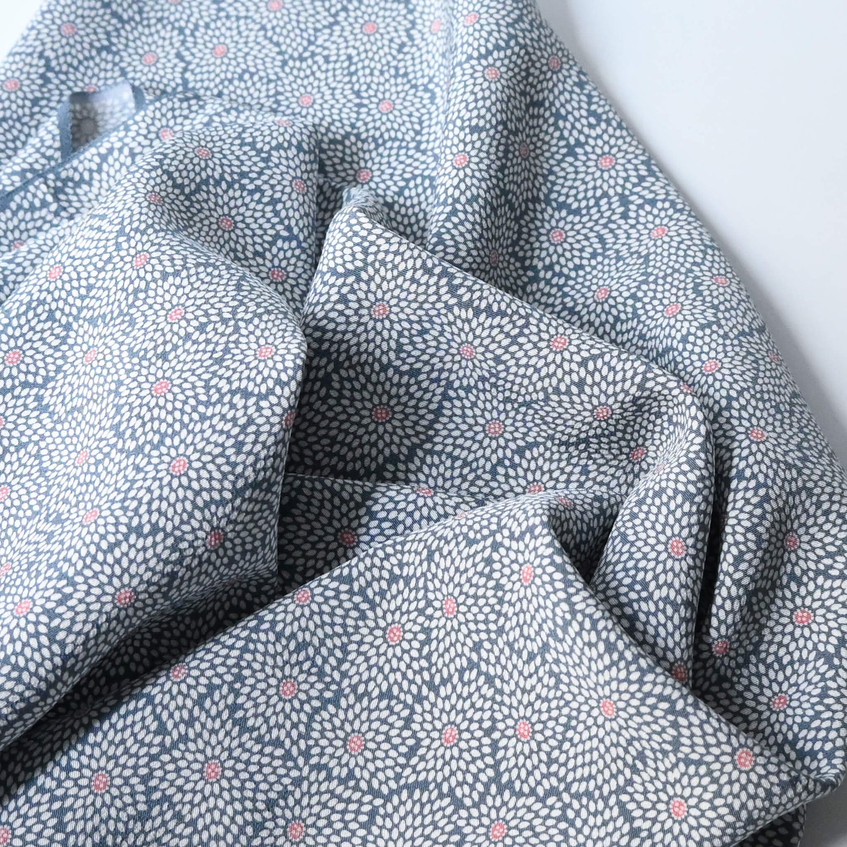 Close-up view of vintage silk crepe kimono fabric in pale grey-blue with all over chrysanthemum pattern.