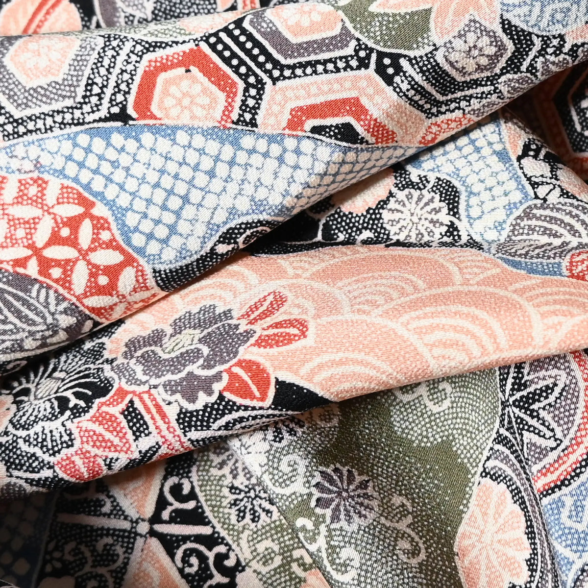 Close-up view of vintage silk crepe kimono fabric with many traditional Japanese seasonal flowers and auspicious motifs in multiple colours.
