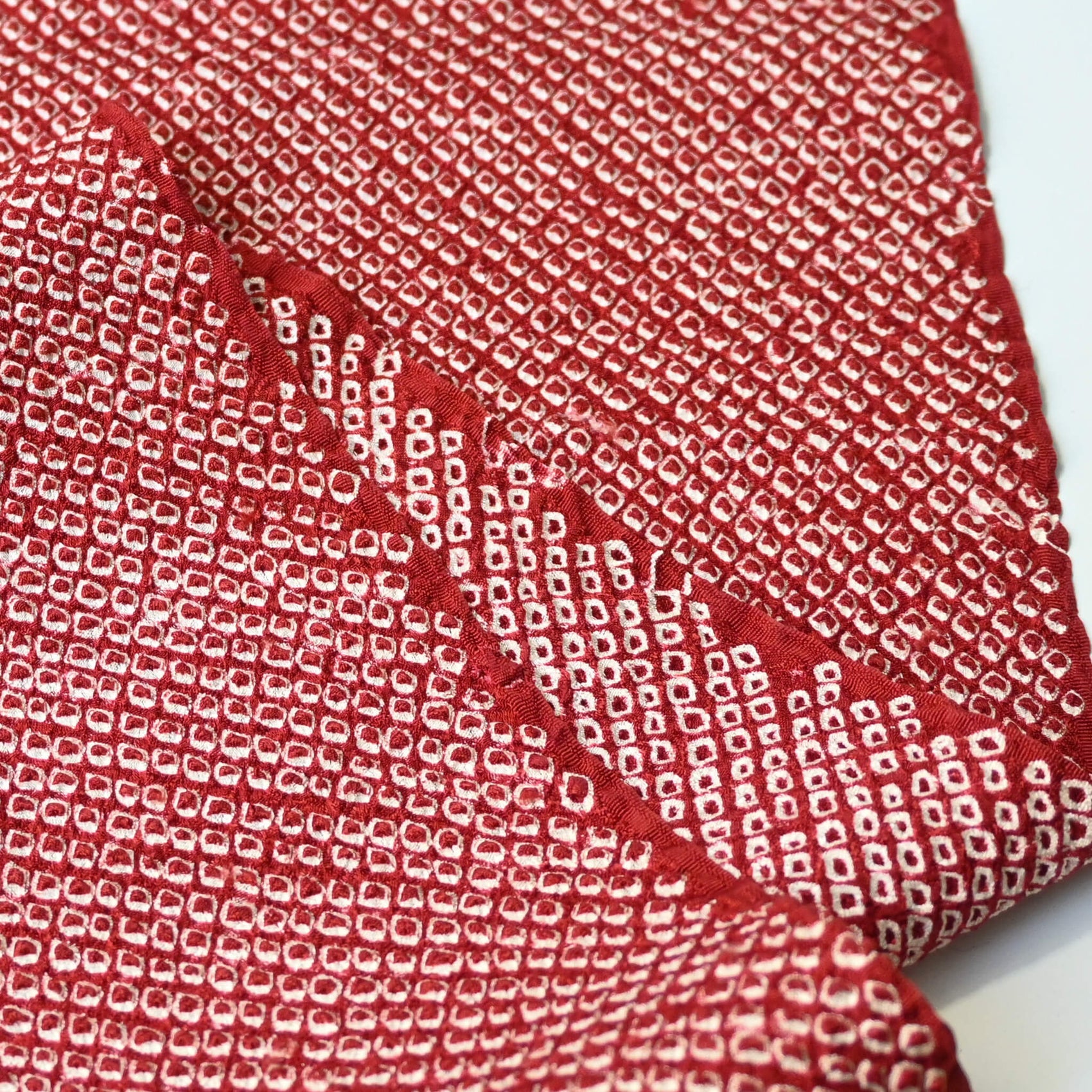 Close-up view of vintage silk kanoko shibori kimono fabric in rich burgundy red.