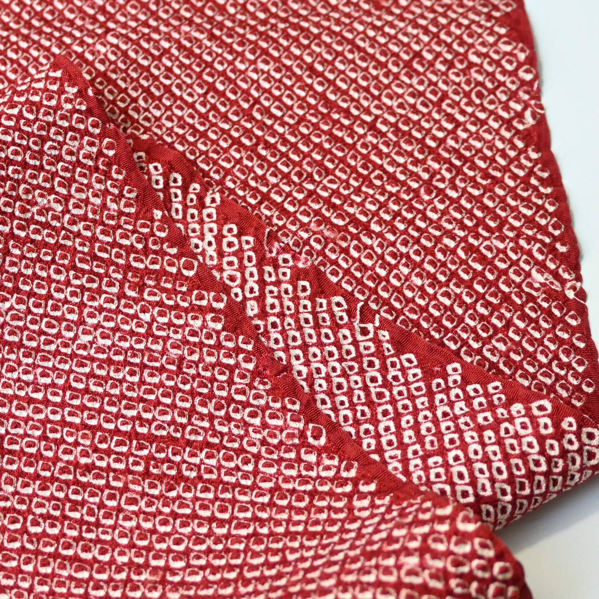 Close-up view of vintage silk kanoko shibori kimono fabric in rich burgundy red.