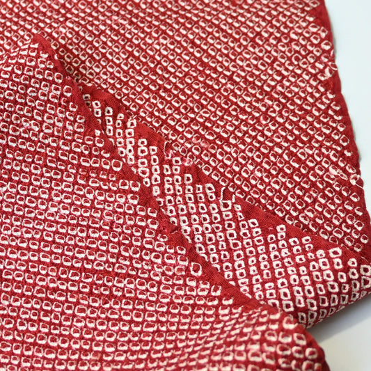 Close-up view of vintage silk kanoko shibori kimono fabric in rich burgundy red.