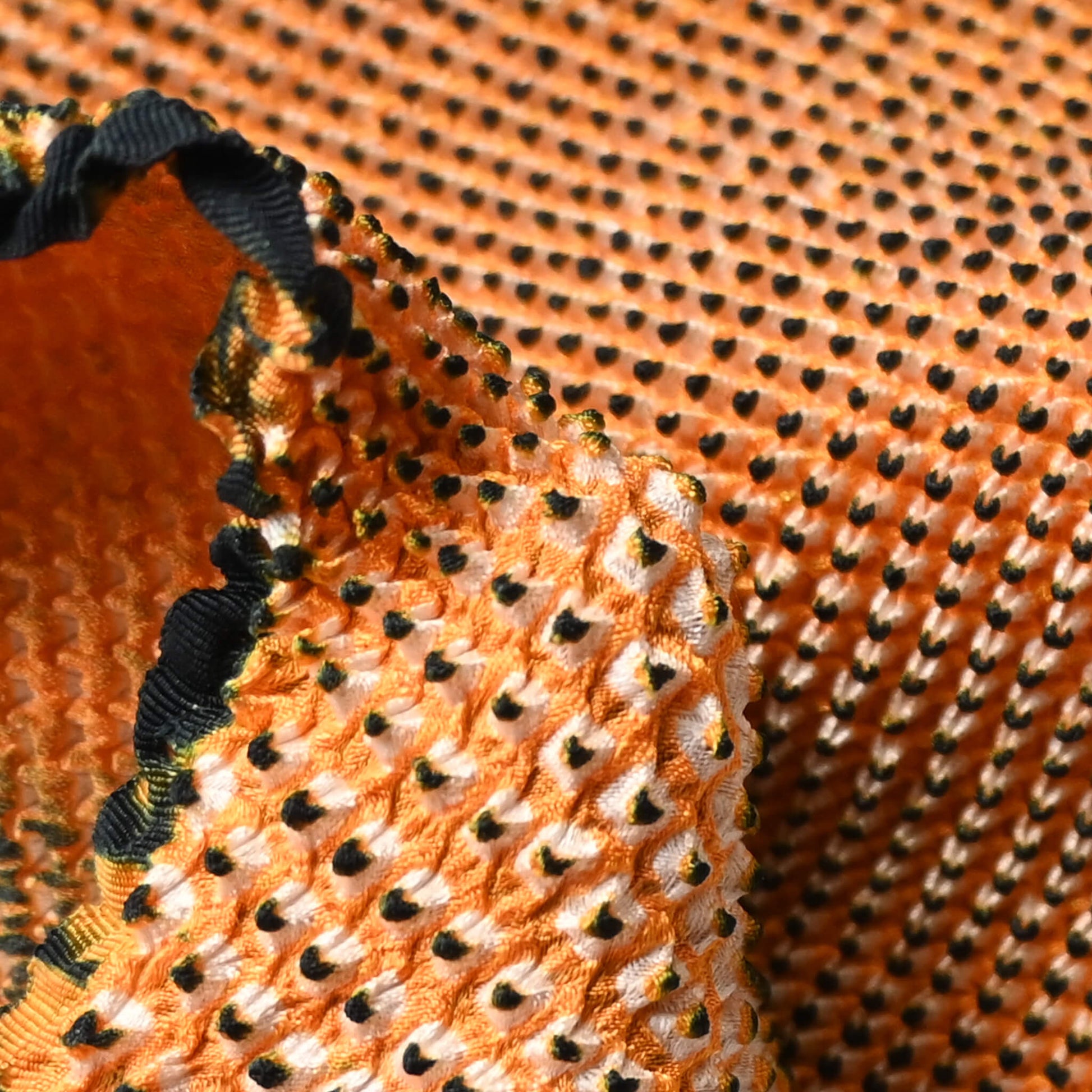 Close-up view of vintage silk shibori kimono fabric bolt in orange and black, unfinished, yunoshimae.