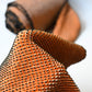 Close-up view of vintage silk shibori kimono fabric bolt in orange and black, unfinished, yunoshimae.