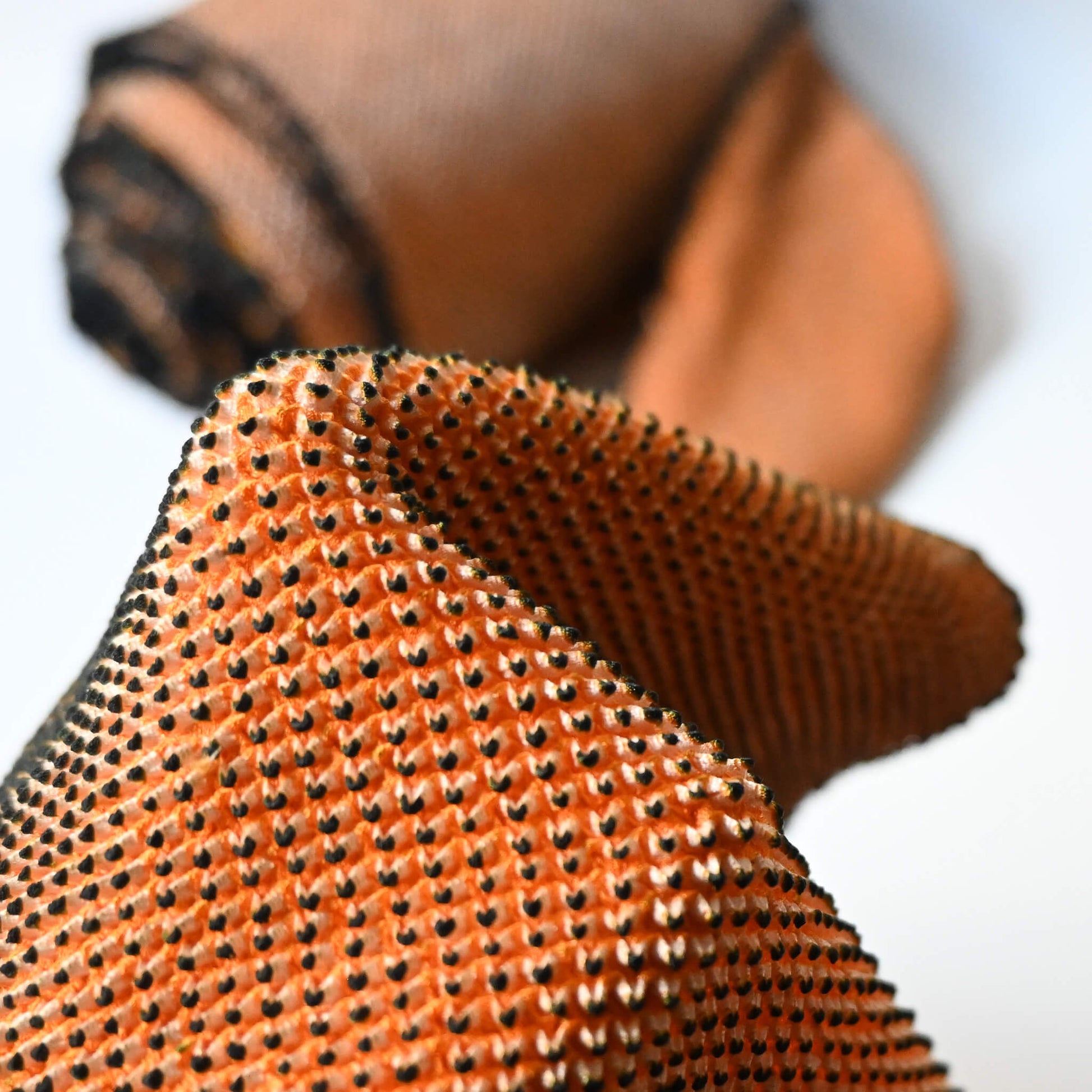 Close-up view of vintage silk shibori kimono fabric bolt in orange and black, unfinished, yunoshimae.
