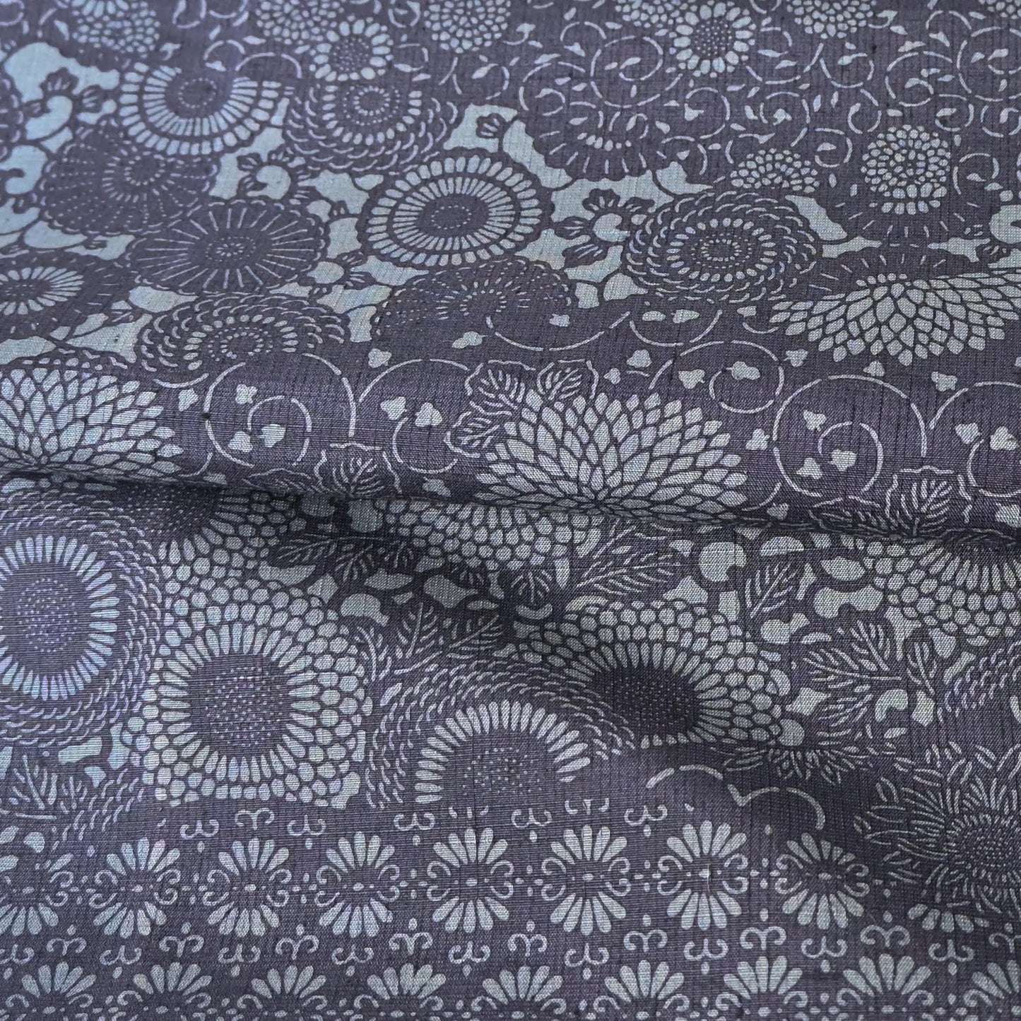 Detailed view of vintage tsumugi silk kimono fabric with katazome floral arabesque pattern in soft indigo tones.