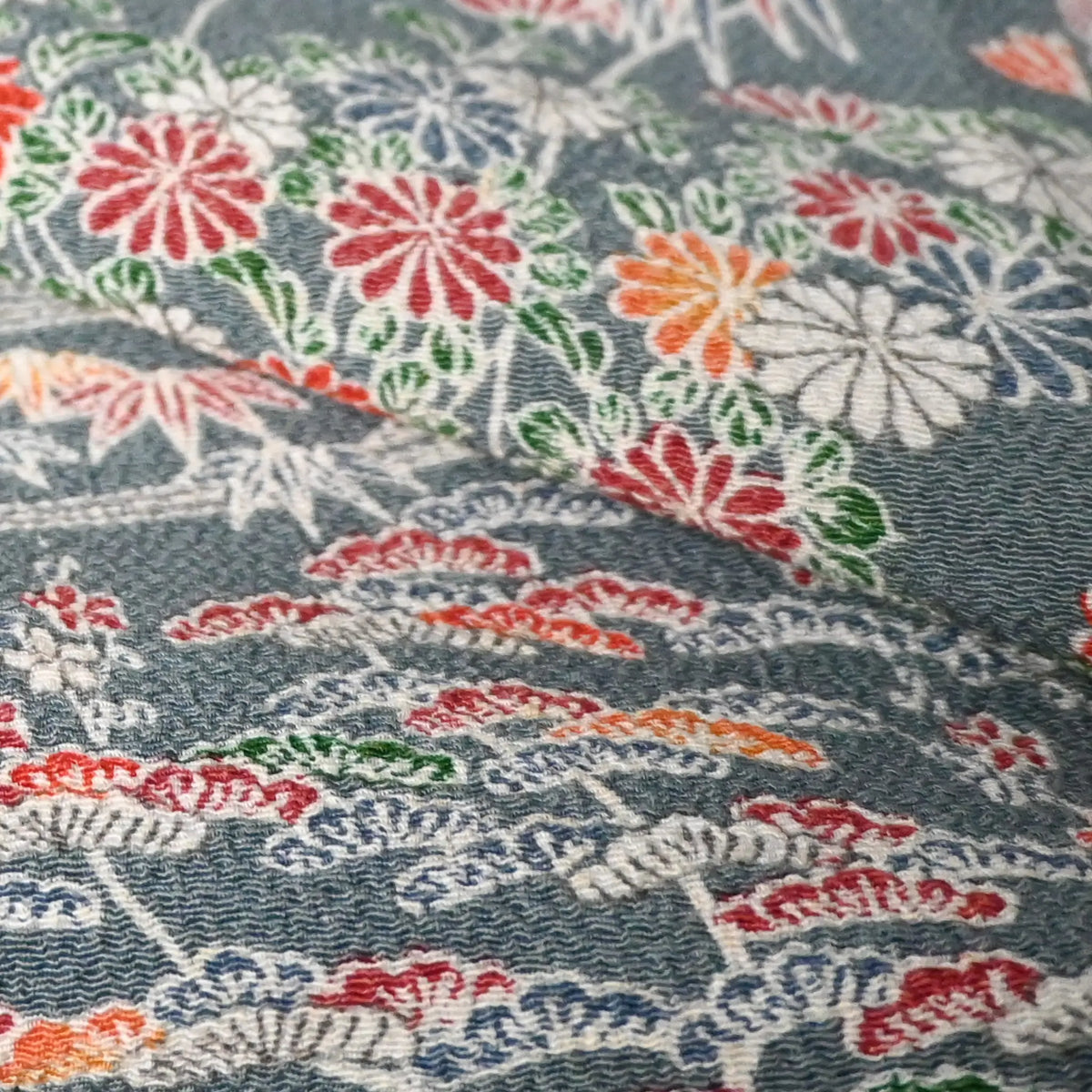 Detailed view of vintage Japanese heavy silk crepe Chirimen kimono fabric in slate grey with gorgeous floral pattern.