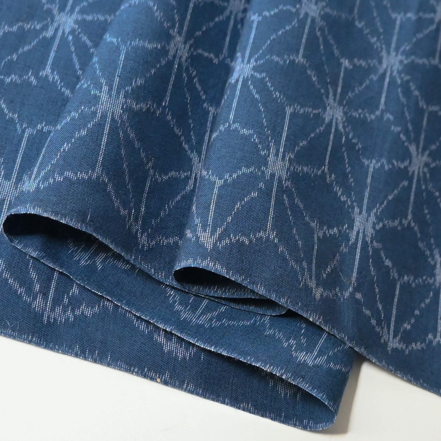 Close-up view of vintage soft blue cotton kimono fabric with Asanoha hemp leaf motif, sold by the metre.