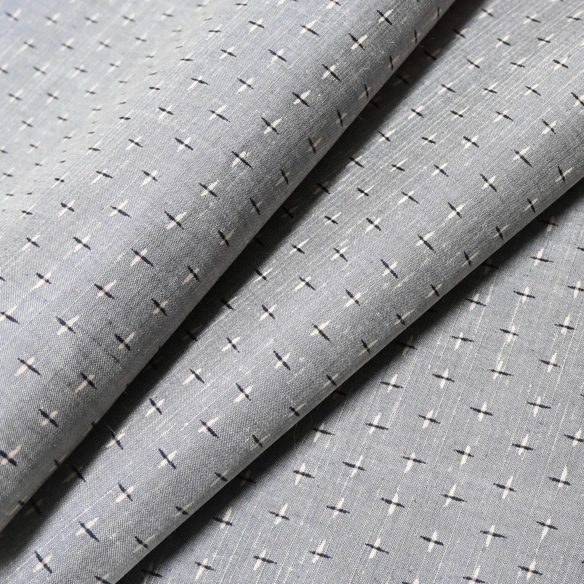 Close-up view of vintage soft blue-grey tsumugi kimono silk with small kasuri crosshatch pattern.