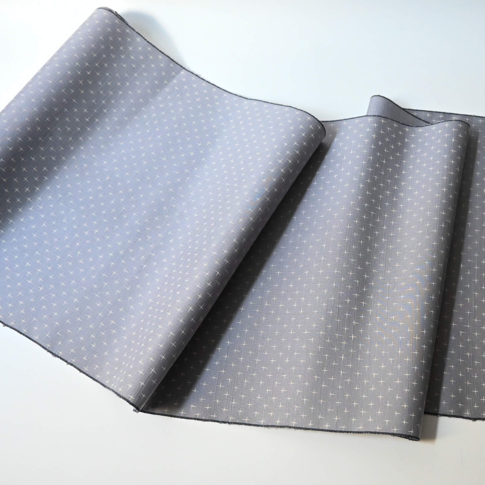 Full view of vintage tsumugi silk kimono fabric sold by the metre in soft grey lilac tone with cross motif.