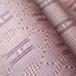 Close-up view of vintage mauve tsumugi silk kimono fabric roll with geometric pattern.
