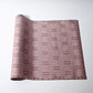 Vintage mauve tsumugi silk kimono fabric roll with geometric pattern.