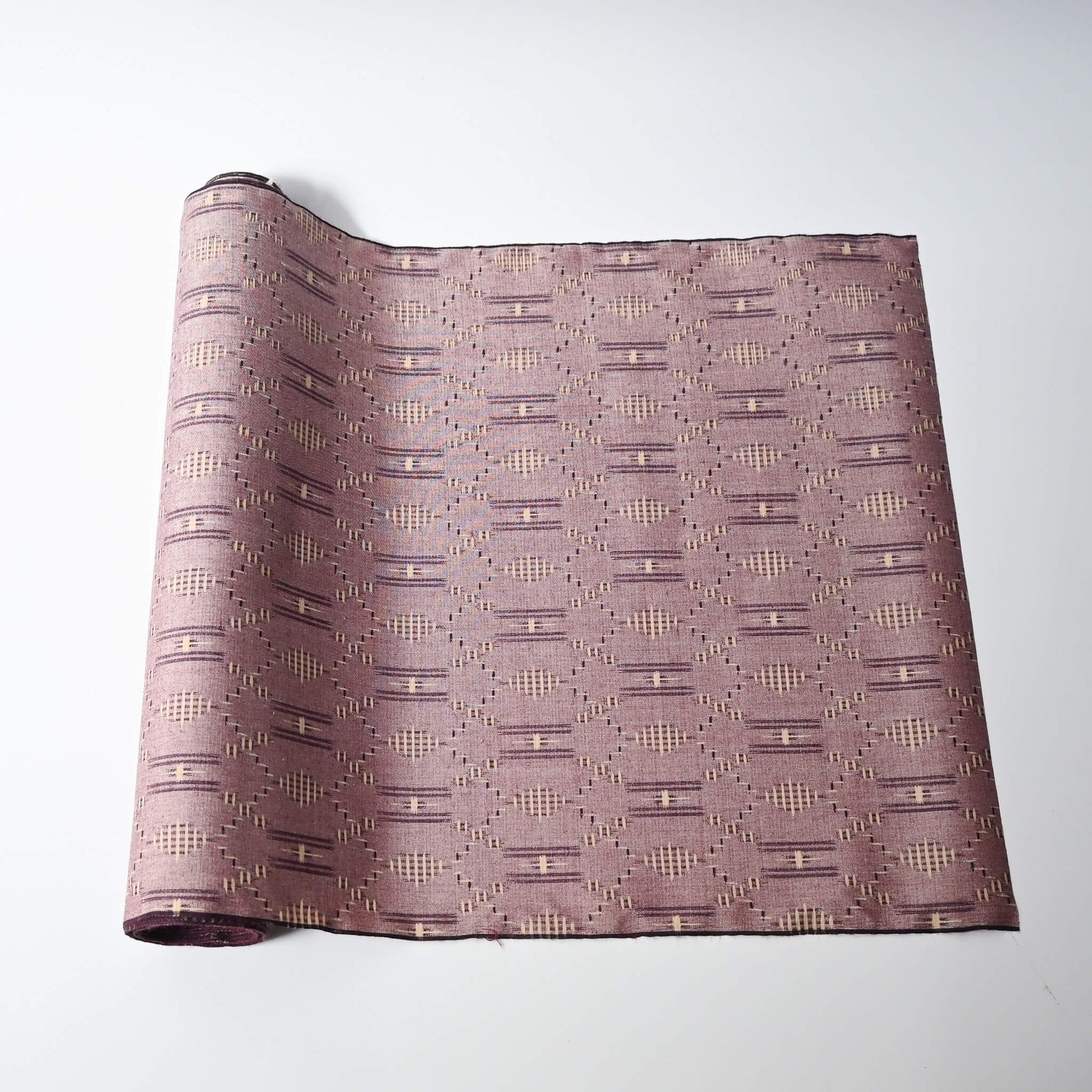 Vintage mauve tsumugi silk kimono fabric roll with geometric pattern.