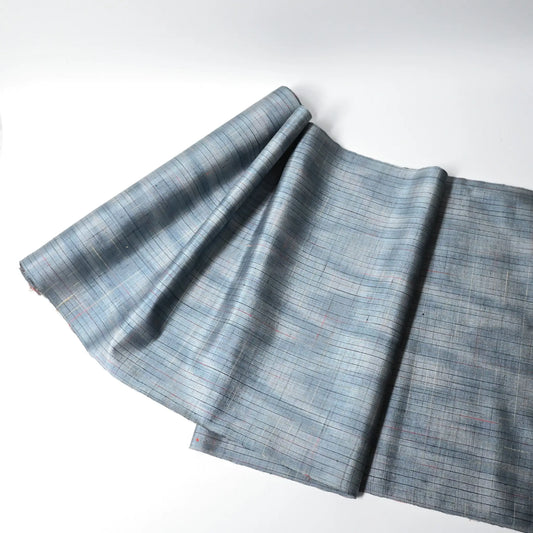 Full view of vintage Japanese tsumugi silk kimono fabric roll in stone blue with sheen.