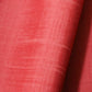 Detailed view of vintage strawberry red tsumugi silk kimono fabric sold by the metre.