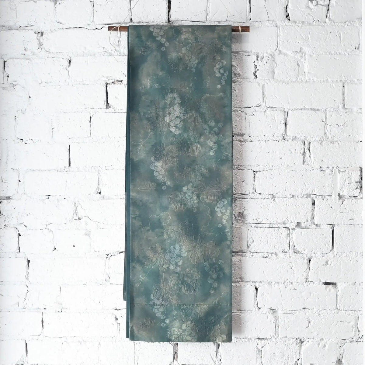 Hanging view of vintage muted teal blue silk Fukure-ori obi with grape vine motif.