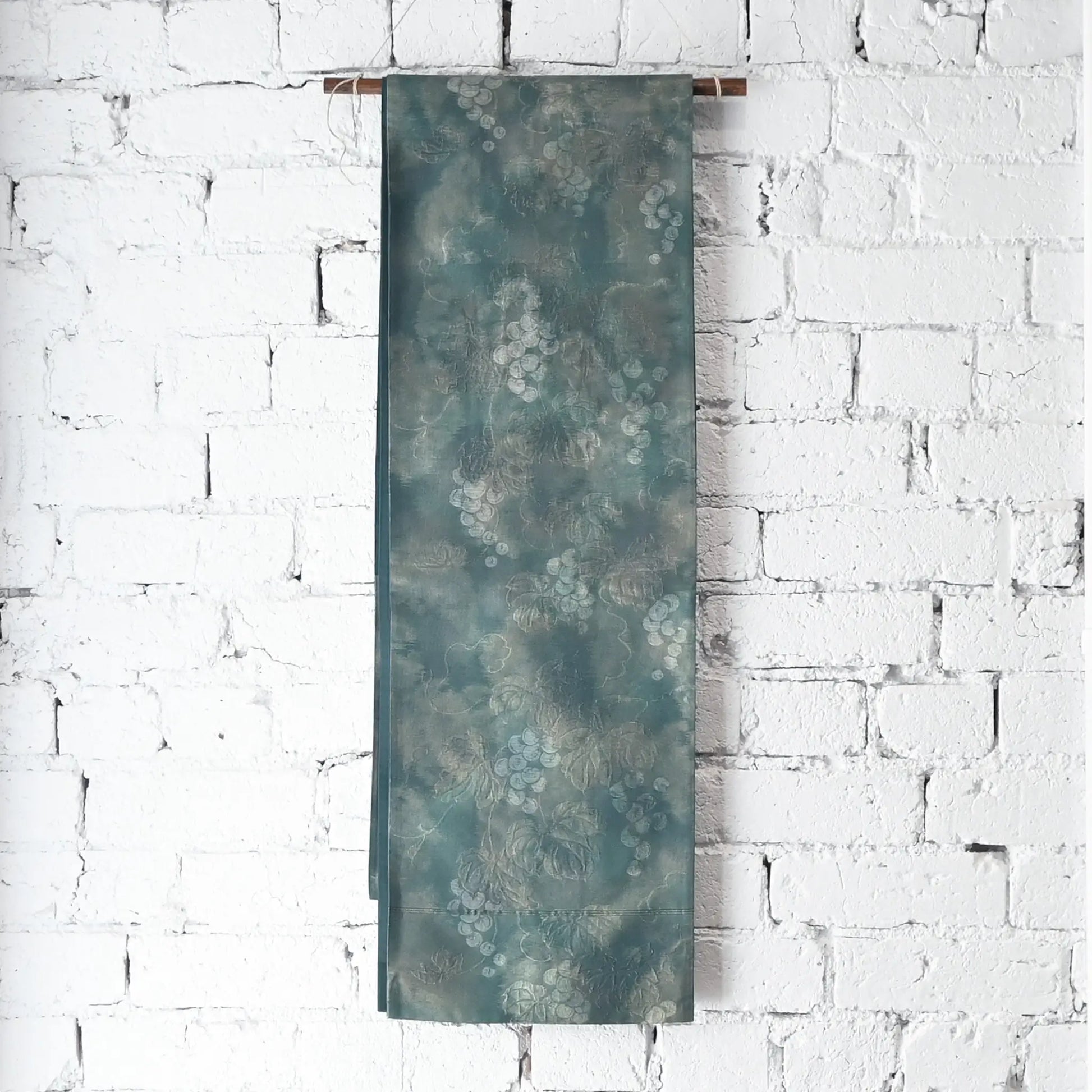 Hanging view of vintage muted teal blue silk Fukure-ori obi with grape vine motif.