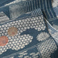 Close-up view of vintage muted blue tsumugi silk kimono fabric piece with houses and chrysanthemum accents.