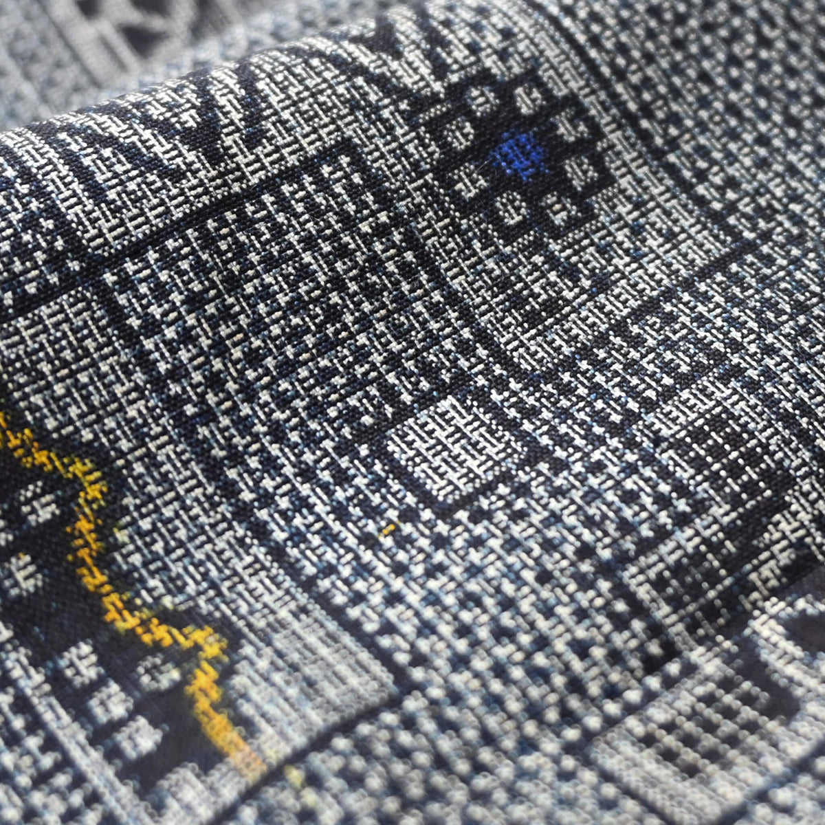 Close-up view of vintage tsumugi silk kimono fabric with intricate woven geometric pattern.