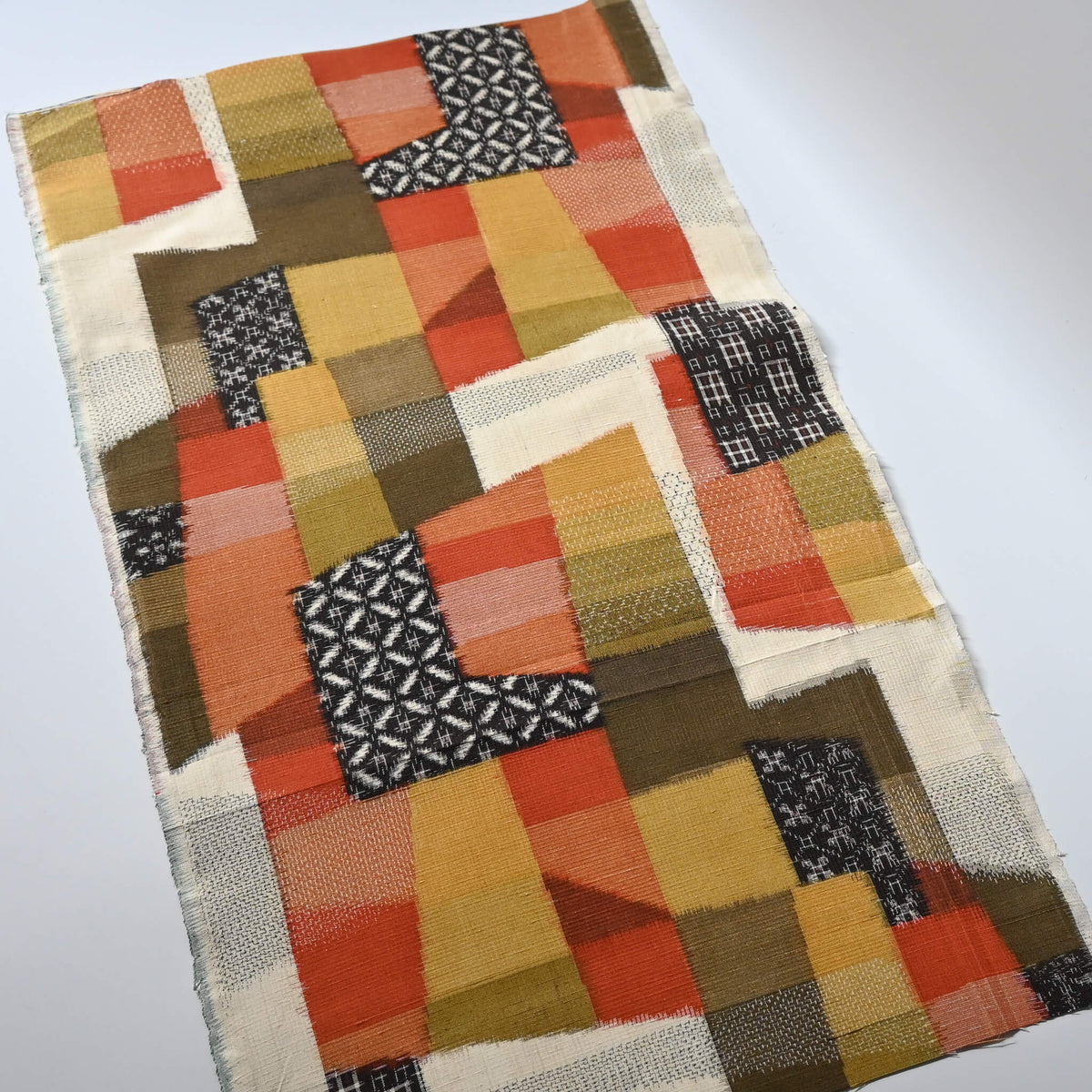 Full view of vintage textured tsumugi silk kimono fabric with  an abstract geometric design in warm shades.