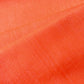 Close-up view of vintage tsumugi silk kimono fabric in vibrant vermillion orange sold by the metre.