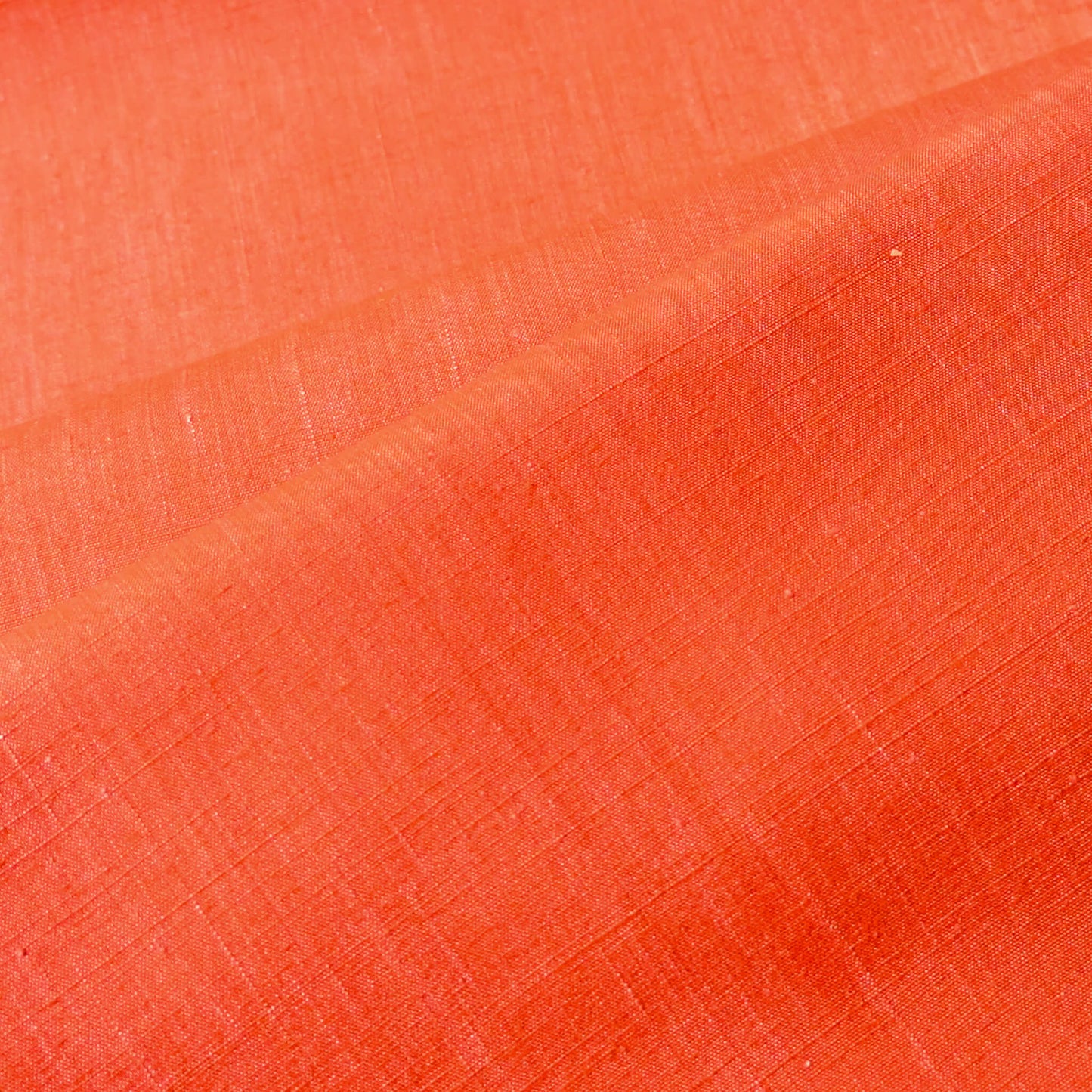 Close-up view of vintage tsumugi silk kimono fabric in vibrant vermillion orange sold by the metre.
