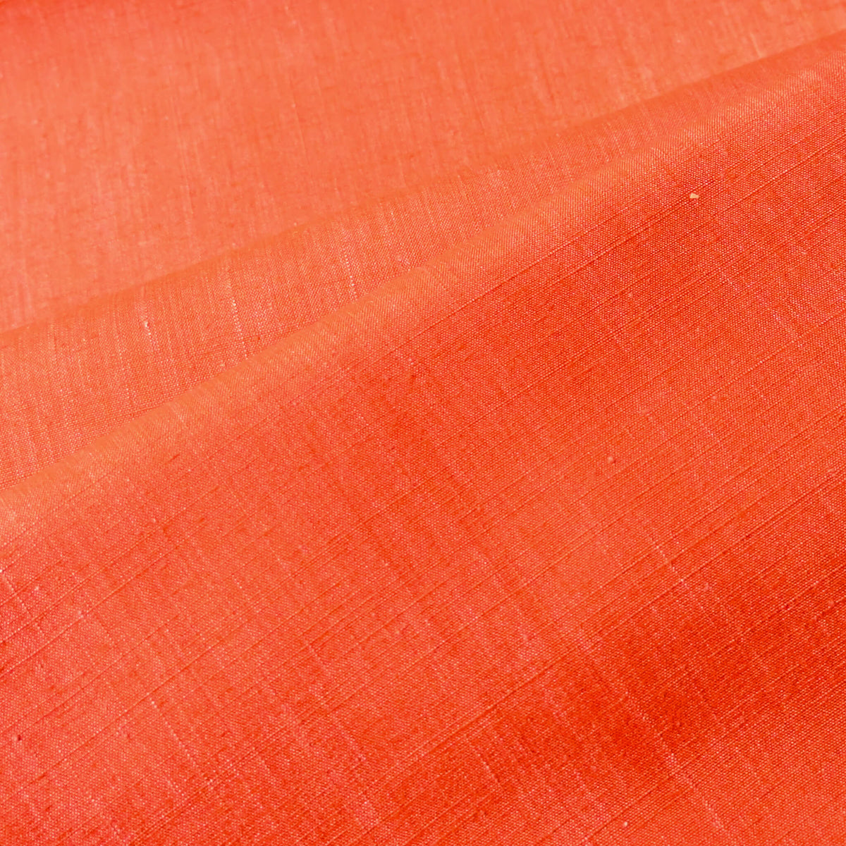 Close-up view of vintage tsumugi silk kimono fabric in vibrant vermillion orange sold by the metre.