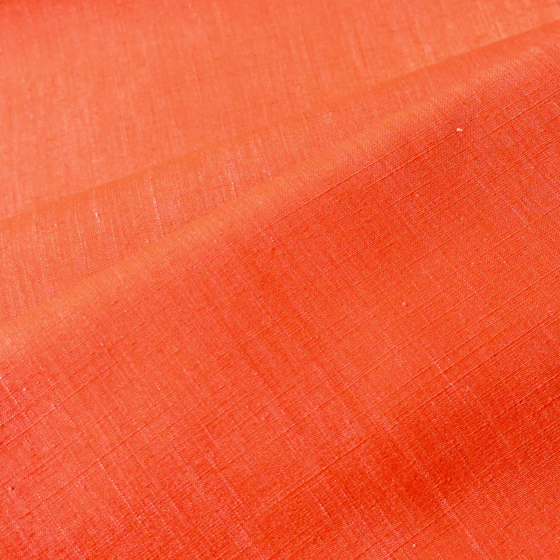Close-up view of vintage tsumugi silk kimono fabric in vibrant vermillion orange sold by the metre.
