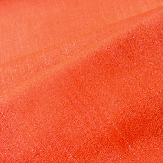 Close-up view of vintage tsumugi silk kimono fabric in vibrant vermillion orange sold by the metre.