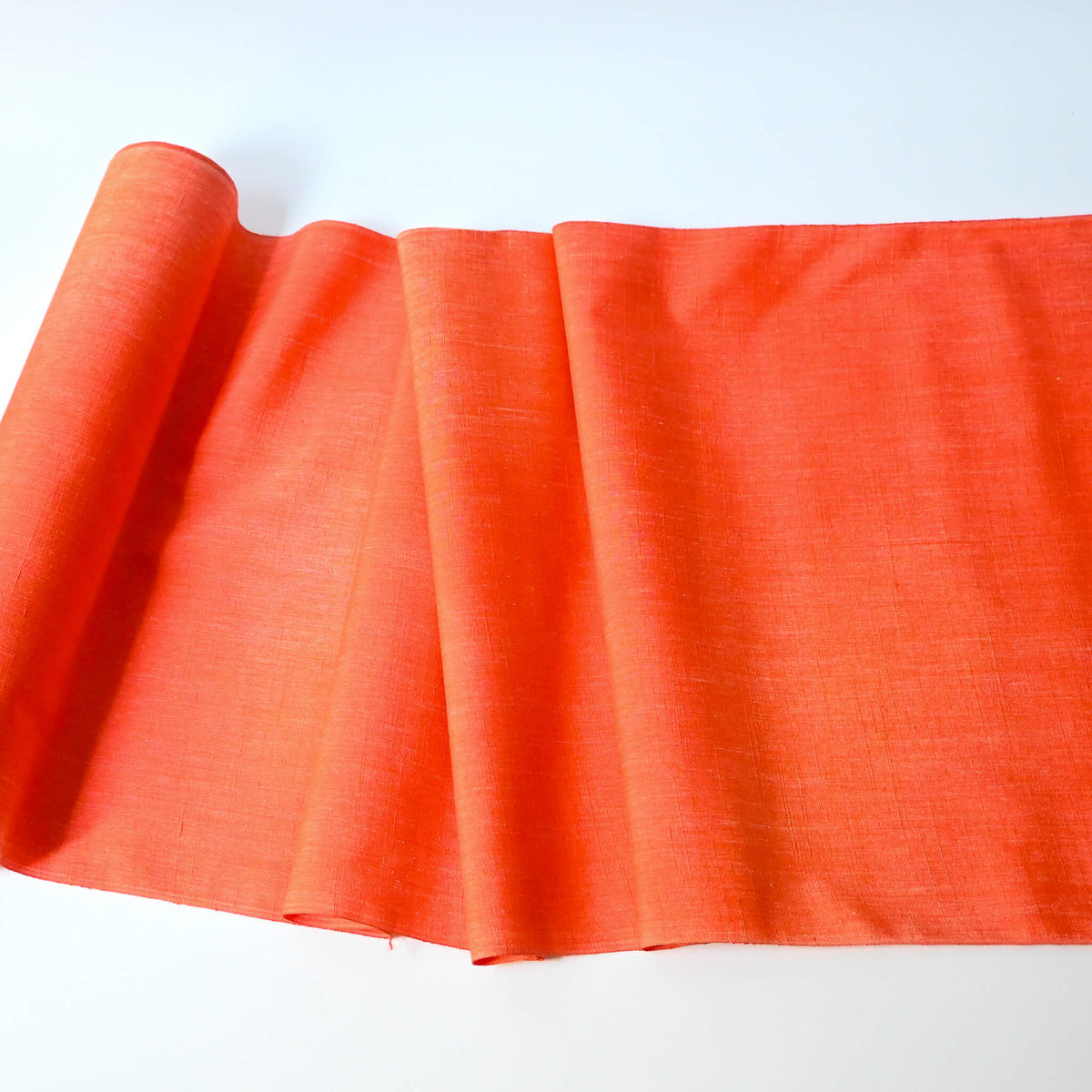 Full view of vintage tsumugi silk kimono fabric in vibrant vermillion orange sold by the metre.