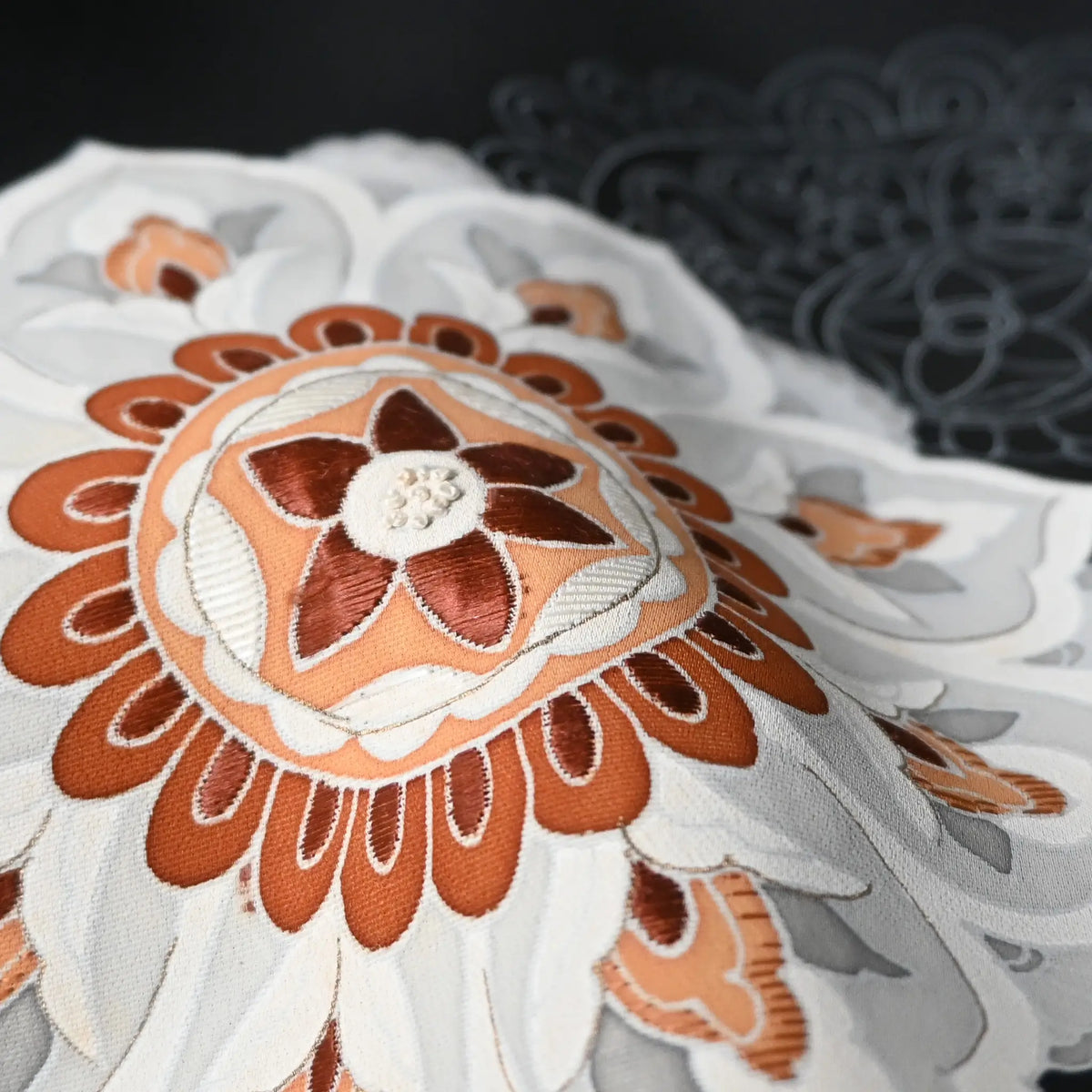 Close-up view of vintage Japanese women's black silk haori with stylised floral motif with embroidery.