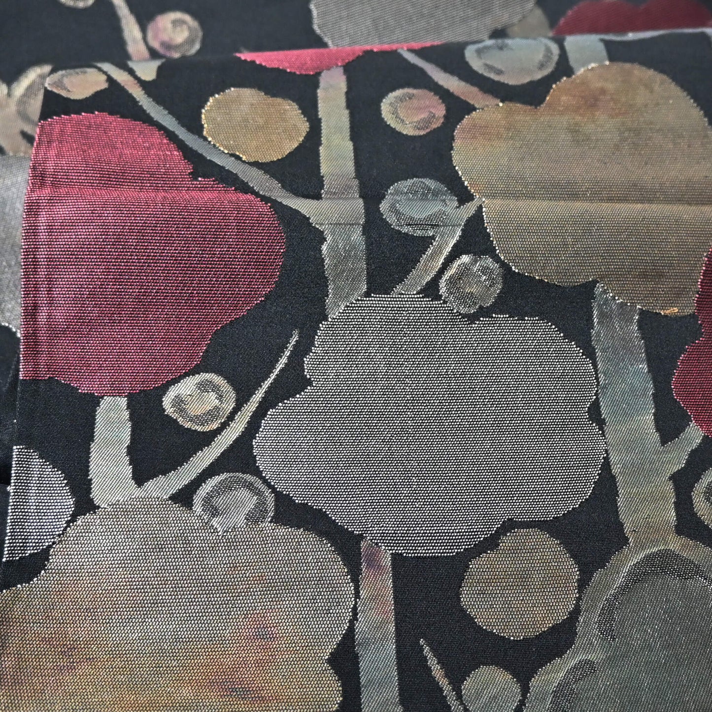 Close-up view of vintage women's silk fukuro obi with stylised plum blossom woven with metallic silver and gold.