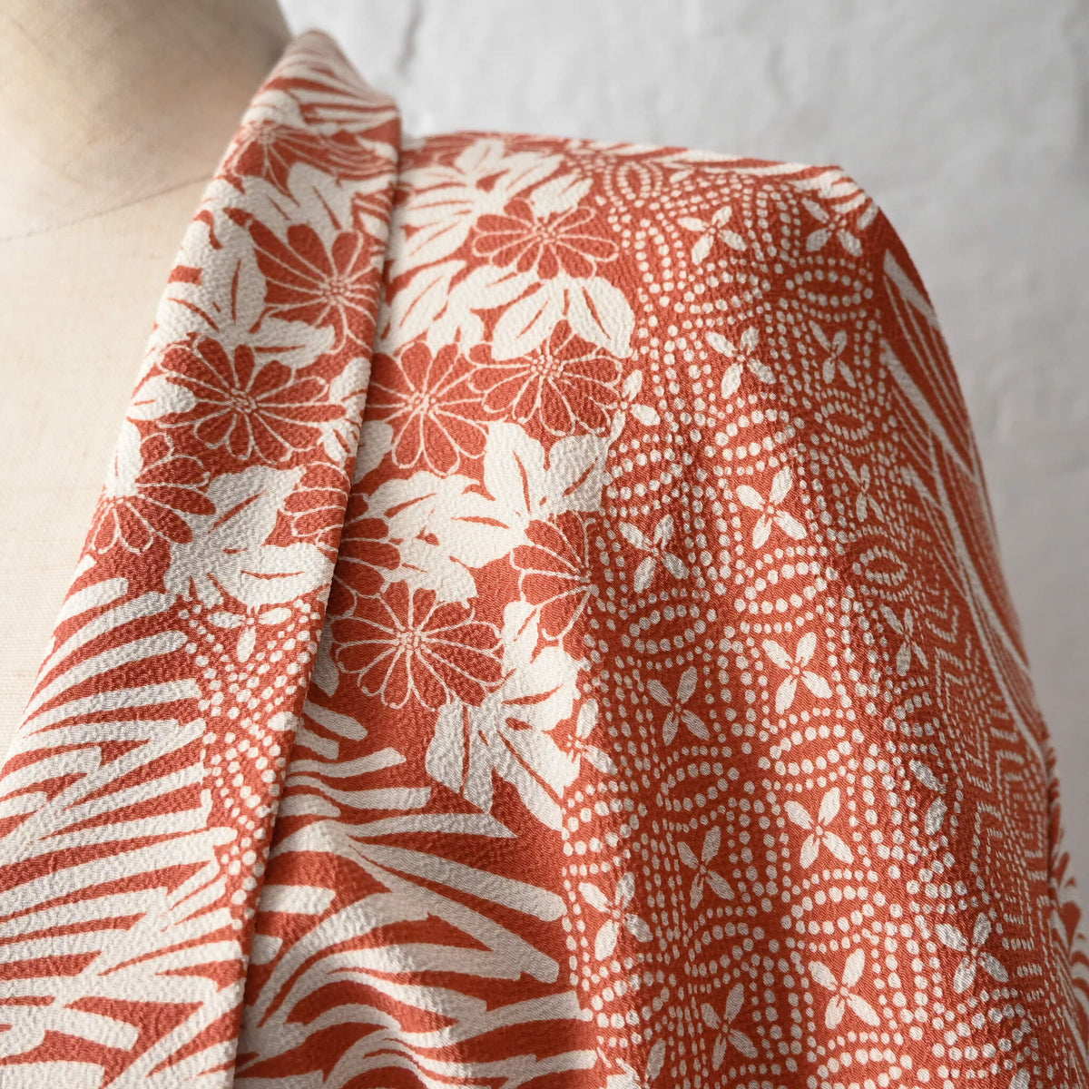 Close-up view of vintage women's synthetic crepe haori in terracotta and ivory with floral and geometric patterns