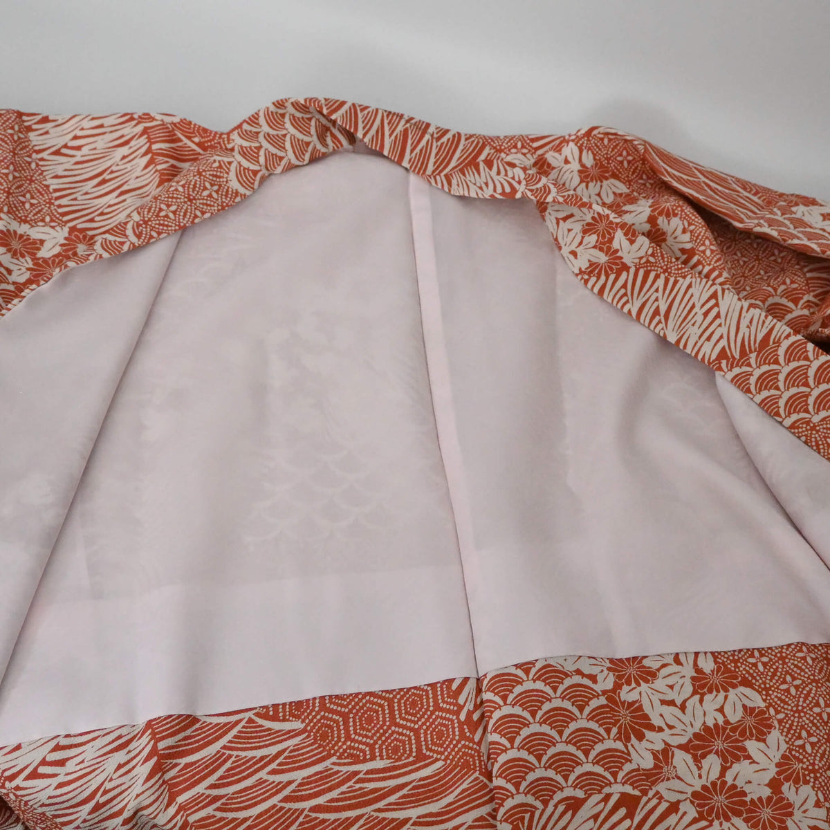 The lining of vintage women's synthetic crepe haori in terracotta and ivory with floral and geometric patterns