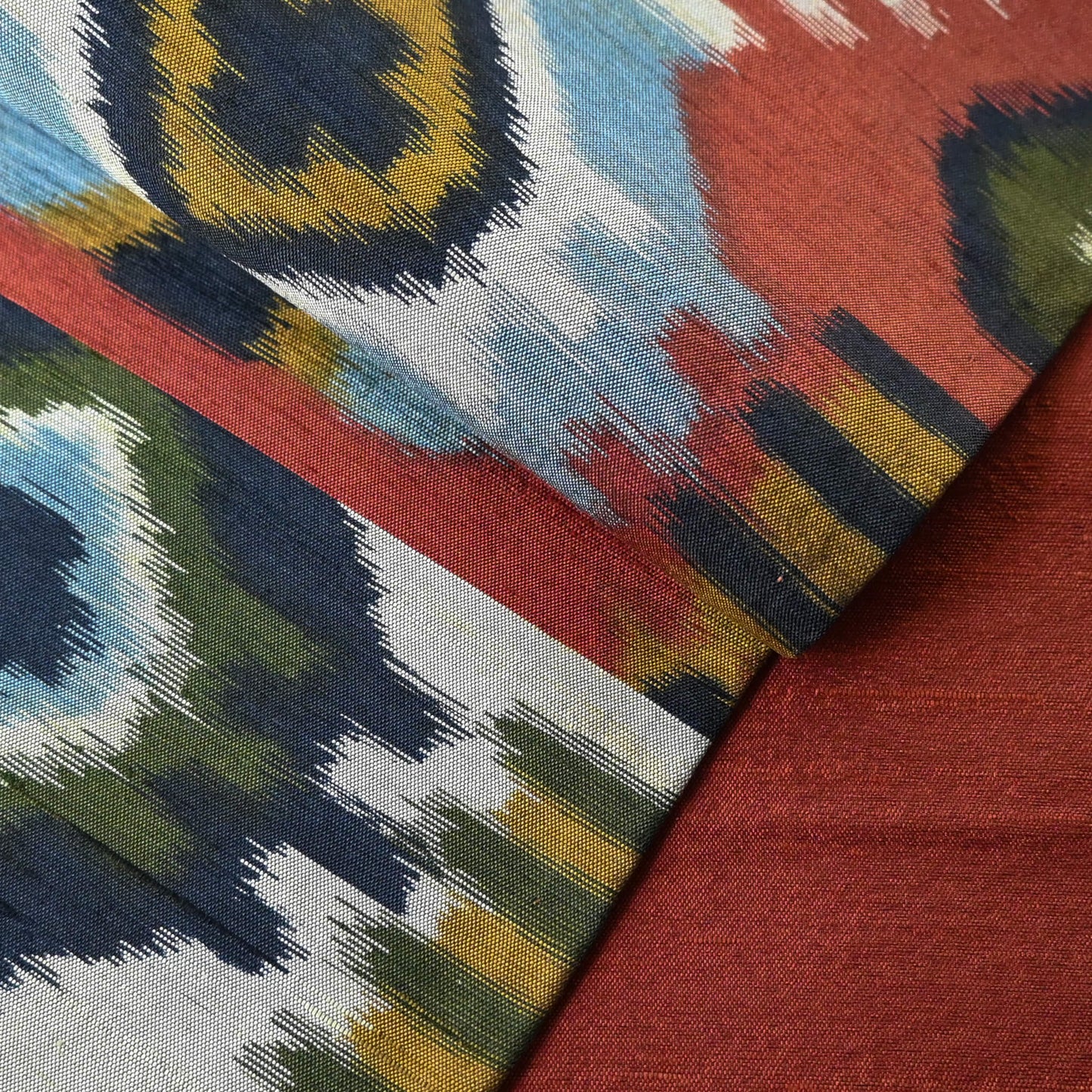 Close-up view of vintage Japanese women's tsumugi silk Fukuro obi with abstract geometric design in rustic orange and green tone.