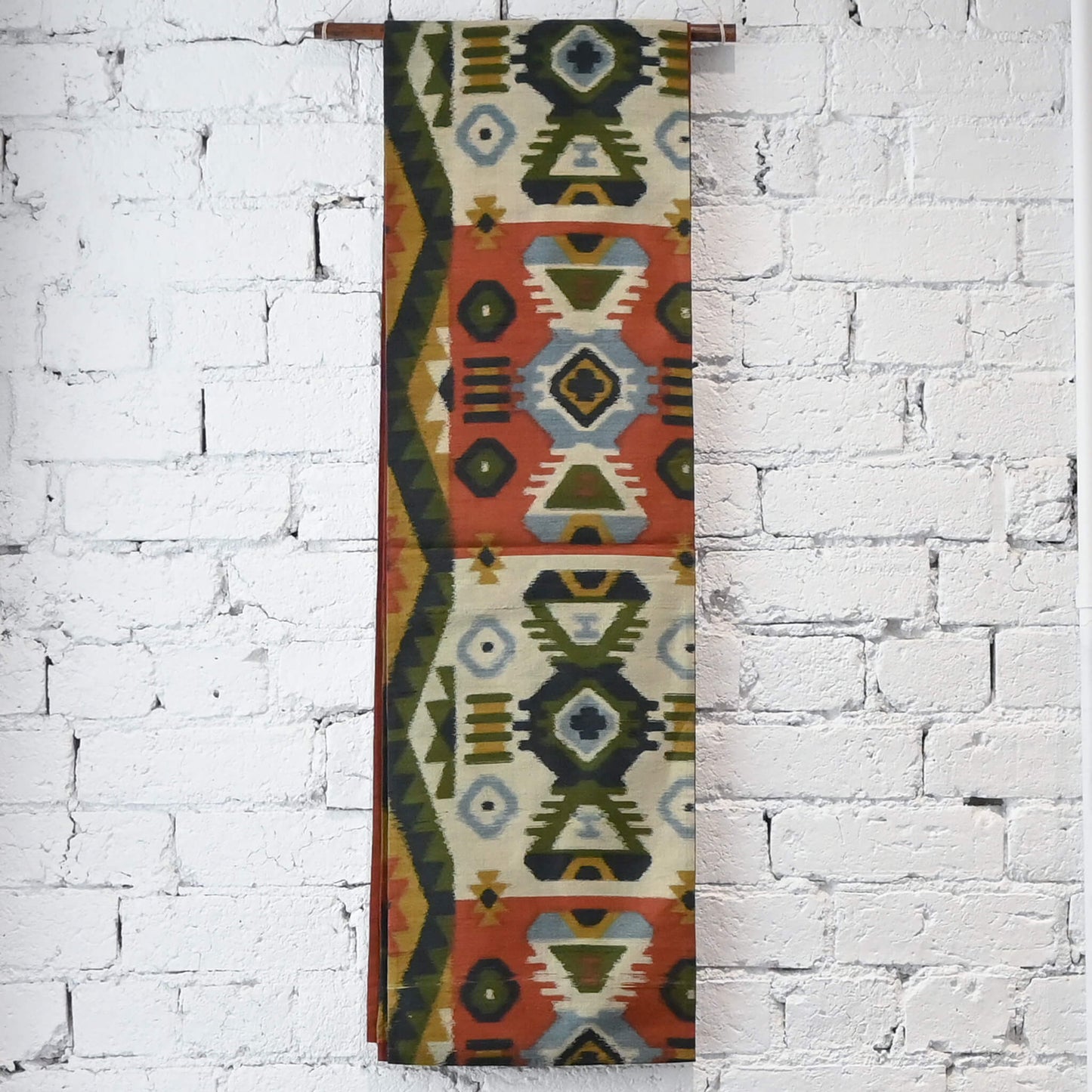 Hanging view of vintage Japanese women's tsumugi silk Fukuro obi with abstract geometric design in rustic orange and green tone.