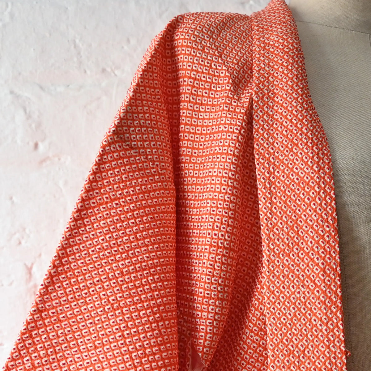 Close-up view of vintage Japanese women's orange silk shibori haori with chrysanthemum motif.