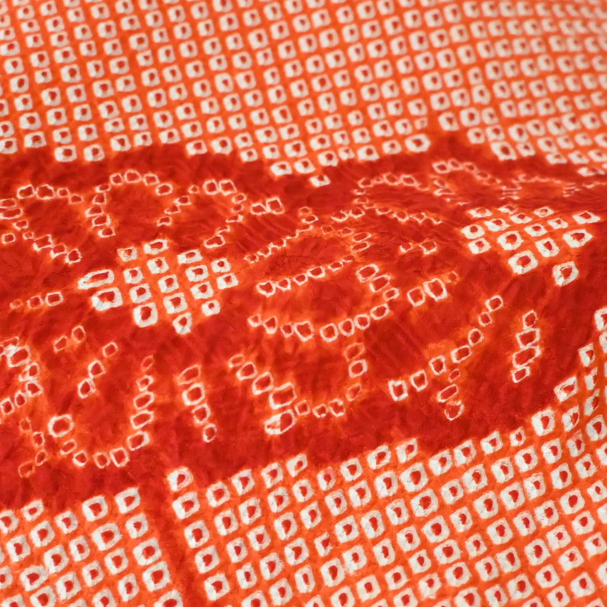 Close-up view of vintage Japanese women's orange silk shibori haori with chrysanthemum motif.
