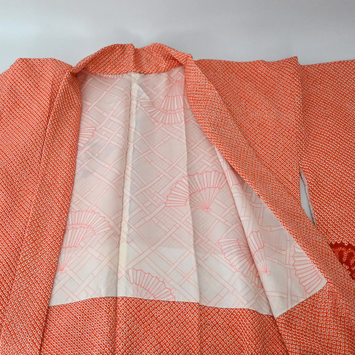 Lining of vintage Japanese women's orange silk shibori haori with chrysanthemum motif.