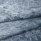 Detailed view of vintage women's tsumugi silk kimono fabric in steel blue with village scenery pattern.