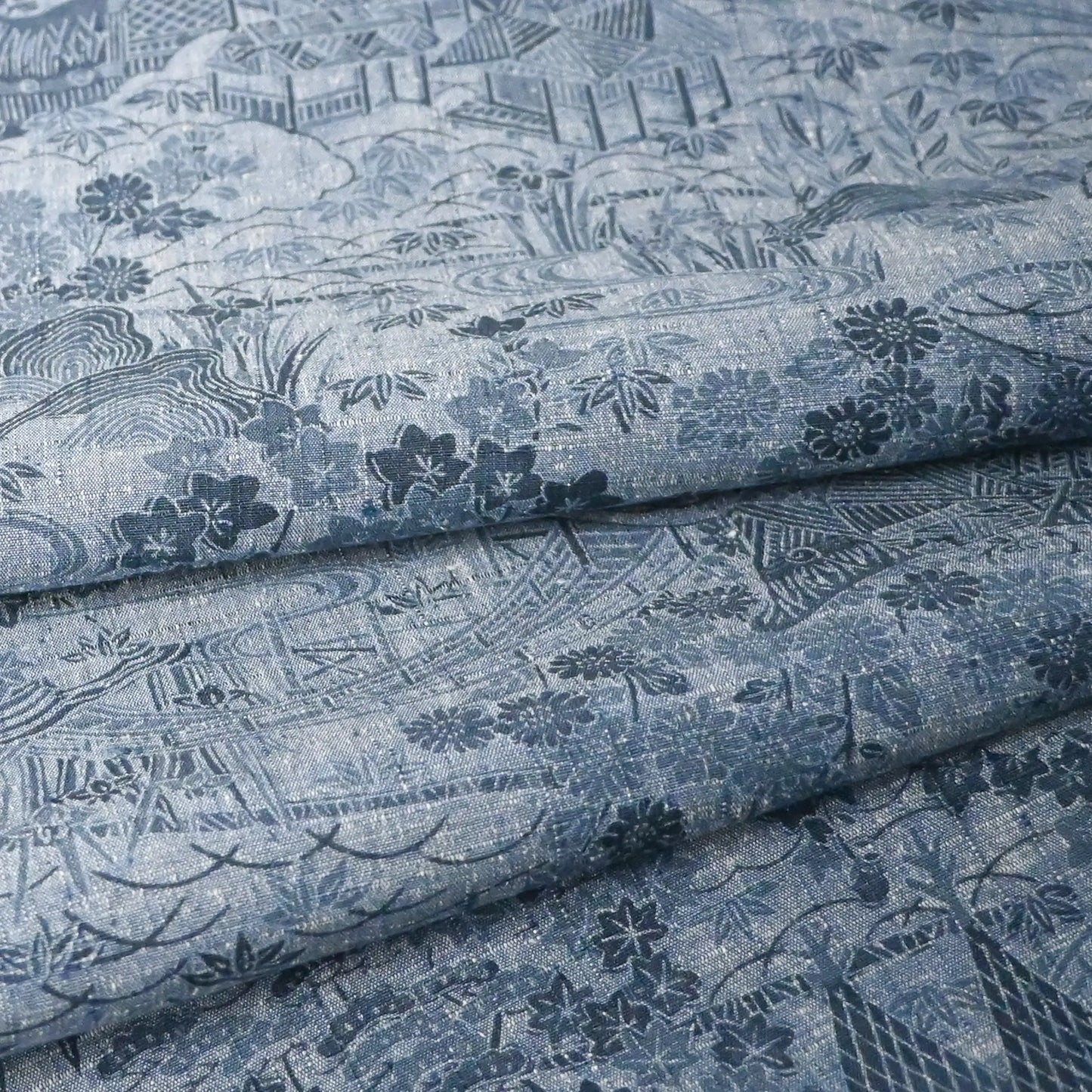 Detailed view of vintage women's tsumugi silk kimono fabric in steel blue with village scenery pattern.