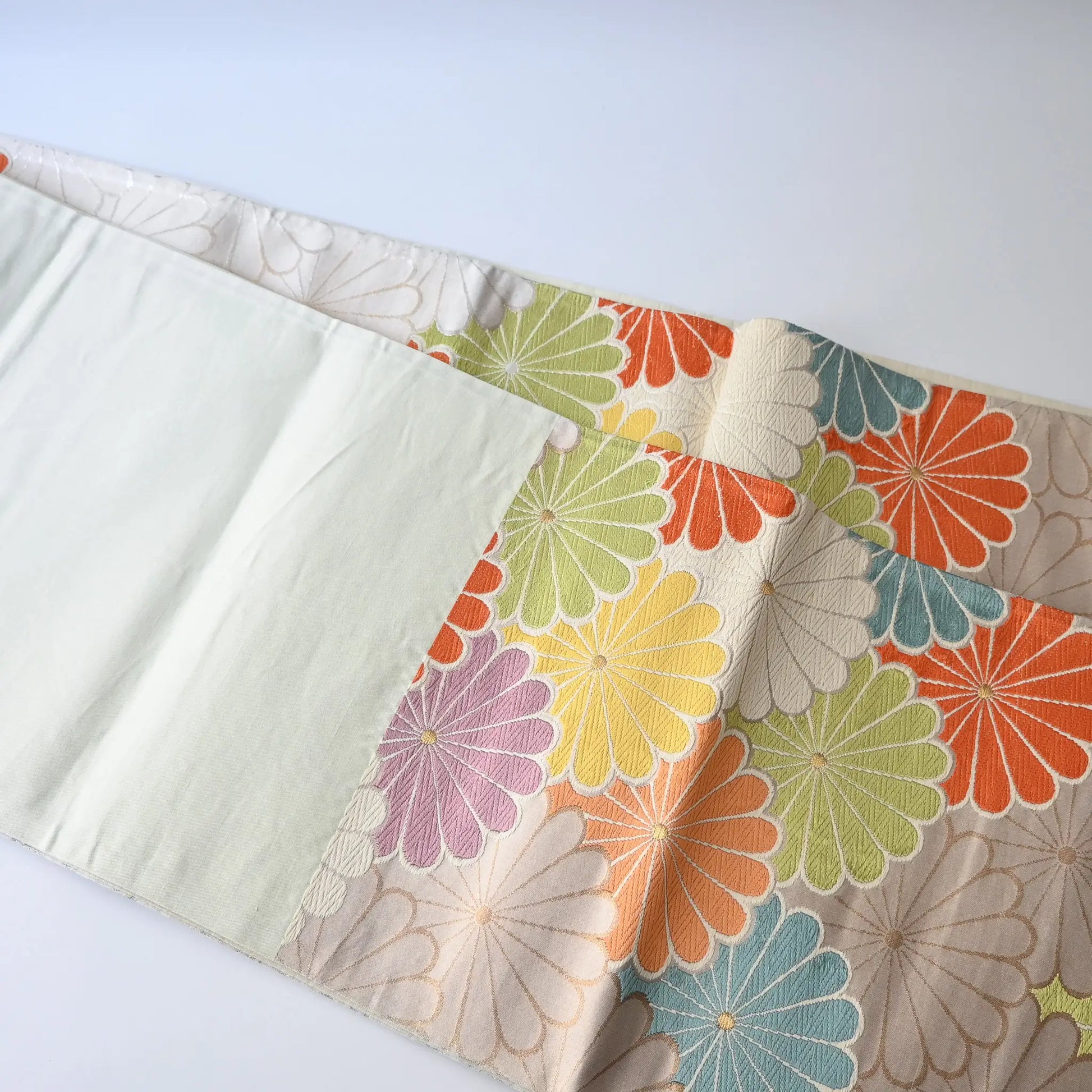Detailed view of vintage women's white silk fukuro obi with colourful chrysanthemum motif.