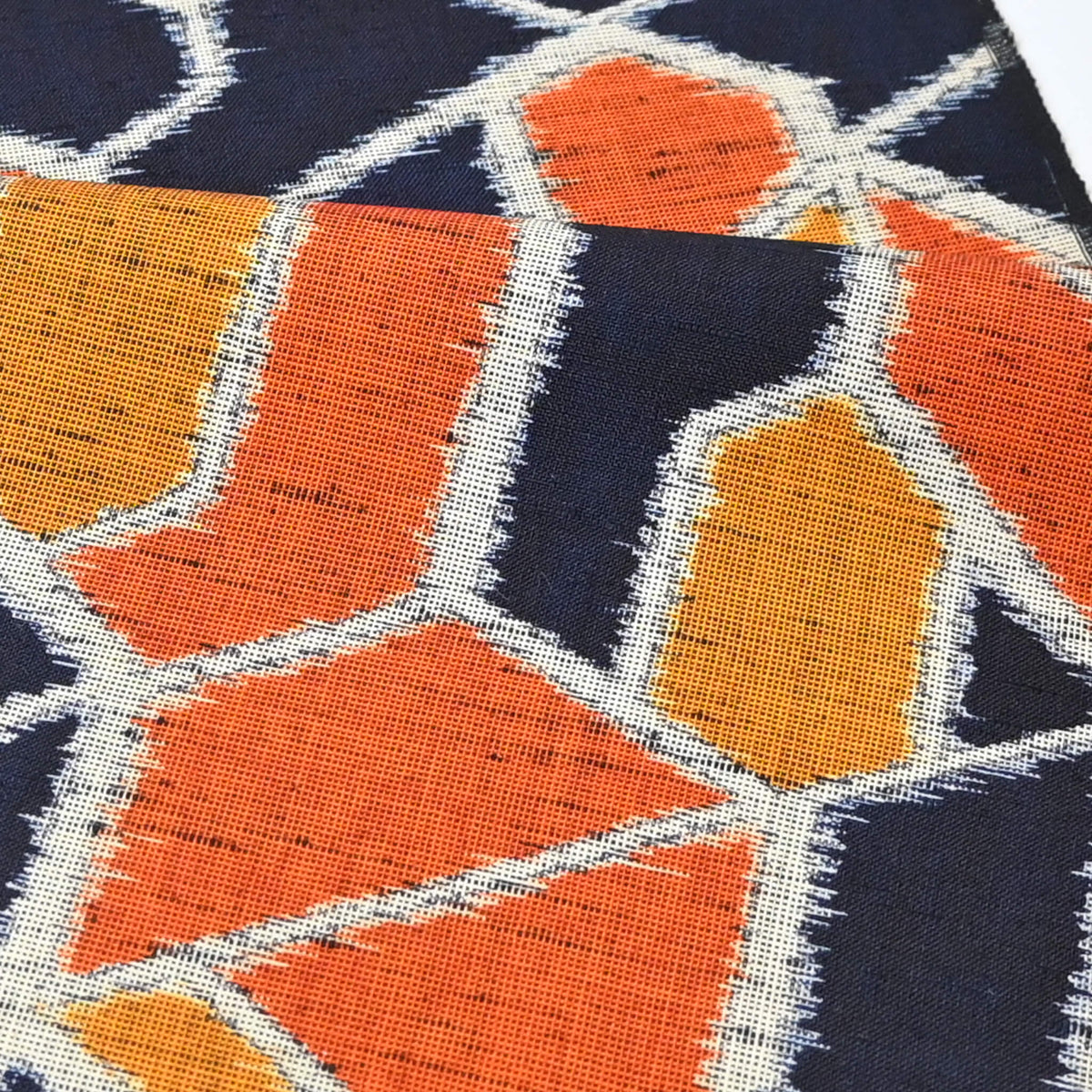Close-up view of vintage wool kimono fabric in navy and orange with geometric modern pattern.