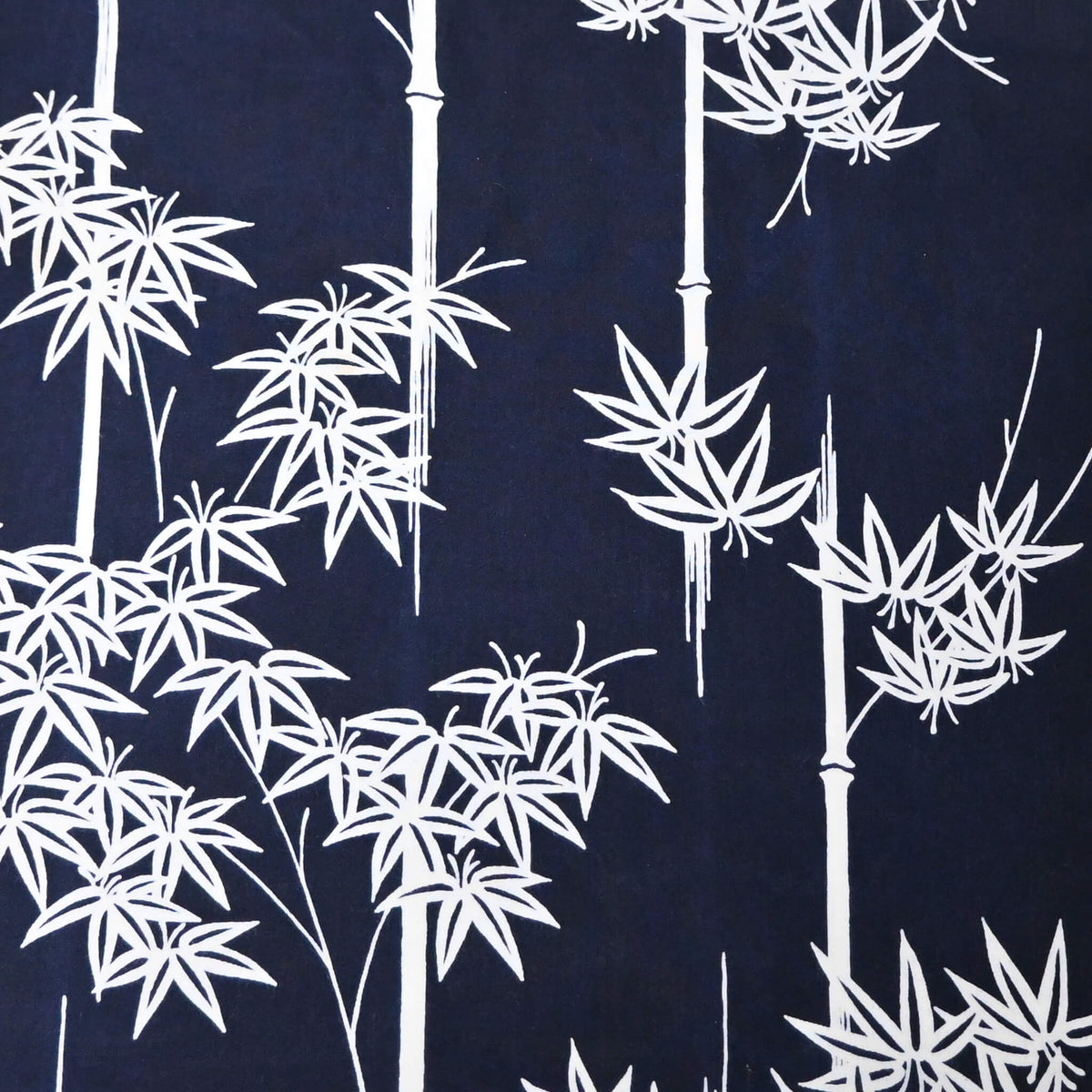 Close-up view of vintage women's yukata cotton fabric with white maple motif on dark indigo base, sold by the metre.